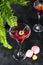 Cosmopolitan or margarita cocktail garnished with a macaroons and berries on a dark background with a green flower