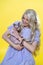 Cosplayer elf young woman smiles happily, holding little Sphinx cat in hands on yellow background
