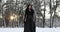 Cosplayer in image of Yennefer from the game or film The Witcher walks in snowy forest at sunset.