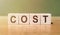 Cost, expense or company profit and loss concept, cube wooden blocks with alphabet combine word COSTS on wooden desk, analyze