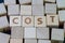 Cost, expense, financial term on money you pay concept, cube wooden block with alphabet combine the word Cost on black chalkboard