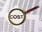 Cost word through magnifier over business documents