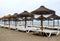 Costa del sol beach in the cloudy weather, end of season. Empty sunbeds and straw umbrellas.