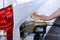 Costa Rica, gas station, woman holding a handful of money by the car, Concept, Rising fuel prices, Refueling cars, Inflation in