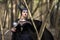 Costume Drama. Marvellous and Magical Maleficent Woman with Horns Posing in Spring Empty Forest with Crook
