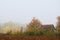 Cottage in autumn forest wrapped in mist.