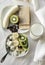 Cottage cheese with banana and kiwi slices, raisins, glass of milk, half banana, half kiwi