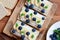 Cottage cheese, bananas and berries sandwiches with crisp bread on wooden board. Great cottage cheese sandwiches recipe. Closeup