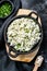 Cottage cheese in a cast-iron bowl with herbs. Organic dairy products. Black background. Top view