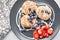 Cottage cheese pancakes or syrniki with blueberry and strawberries on black plate, closeup view. Condensed milk sauce