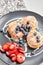 Cottage cheese pancakes or syrniki with blueberry and strawberries on black plate, closeup view. Condensed milk sauce