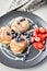 Cottage cheese pancakes or syrniki with blueberry and strawberries on black plate, closeup view. Condensed milk sauce