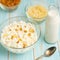 Cottage cheese with raisins and pineapple zucchini, with milk in a bowl on a blue wooden table