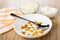 Cottage cheese, sour cream in bowls, napkin, spoon and raisin in plate on table