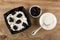 Cottage cheese with sour cream and prunes in bowl, bowl with prune, spoon in bowl with sour cream on wooden table. Top view