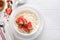 Cottage cheese with strawberries. Breakfast from cottage cheese with slices fresh strawberries, cream, cup of coffee in white bowl