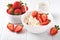 Cottage cheese with strawberries. Breakfast from cottage cheese with slices fresh strawberries, cream, cup of coffee in white bowl