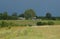Cottage and farm buildings seen across the field.