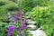 Cottage garden stone steps between summer flowers and plants