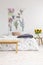 Cottage house minimal bedroom interior with colorful flowers and birds painted on fabric above a bed which is dressed in natural t