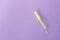 Cotton tampon with light green opened applicartor on violet background. Woman days hygiene protection. Menstrual cycle period