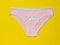 Cotton women`s pink panties on a bright yellow background close-up. Beautiful lingerie. The view from the top