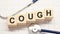 cough word written on wooden blocks and stethoscope on light white background