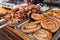 A counter with metal trays containing grilled sausages and meat. Food and cooking equipment at a street food festival