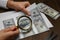 Counterfeiter examining sheet of paper with dollar banknotes at wooden table, closeup. Fake money concept