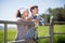 Country couple of farmers drink milk in field near fenc