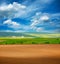 Country dry plowed earth agricultural green farmland on blue sky