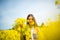 Country girl in a good mood walks in a rape field