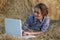 Country girl lying on hay with laptop