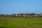 Country life. A village on a hill. A green spring field in front of a modern village on a hill against a clear blue sky