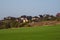 Country life. A village on a hill. A green spring field in front of a modern village on a hill against a clear blue sky