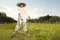 Country man in straw hat mowing grass in sunny day