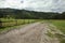 A country road along a wooden fence leads to a distance to the mountains