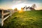 Country road in dutch countryside with white fence leading towards an old farmhouse in Holland during an atmospheric sunset