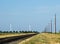 Country road in the empty Texas prairie with power lines and wind turbines behind