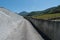 Country road flanked by old rock walls leads through vineyards with young grapevines in summer