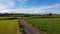 A country road between green fields in Ireland. Blue sky over grass fields. Irish summer landscape. Green grass field under blue