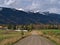 Country road passing a farm near McBride in Robson Valley, Canada with cows, barn and snow-capped Rocky Mountains.