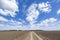 Country road through plowed field and blue sky. Russian landscap