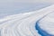 Country road with red ploughing marks in the snow