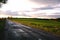 Country road with stormy clouds in sunset rural scene