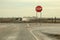 Country Roads - Stop sign with large bullet hole stands by crossroads with pickup truck with trailer driving toward it in a cloud