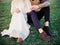 Country wedding. Outdoor portrait of happy beautiful newlyweds sitting on green grass