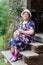 Country woman holding hairless sphynx cat on her knees when sitting on timber veranda