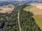 Countryside high way road through forest and near small river from drone view