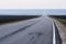 Countryside landscape minimalist style. Empty eneven asphalt road with white road marking in empty black fields in early morning